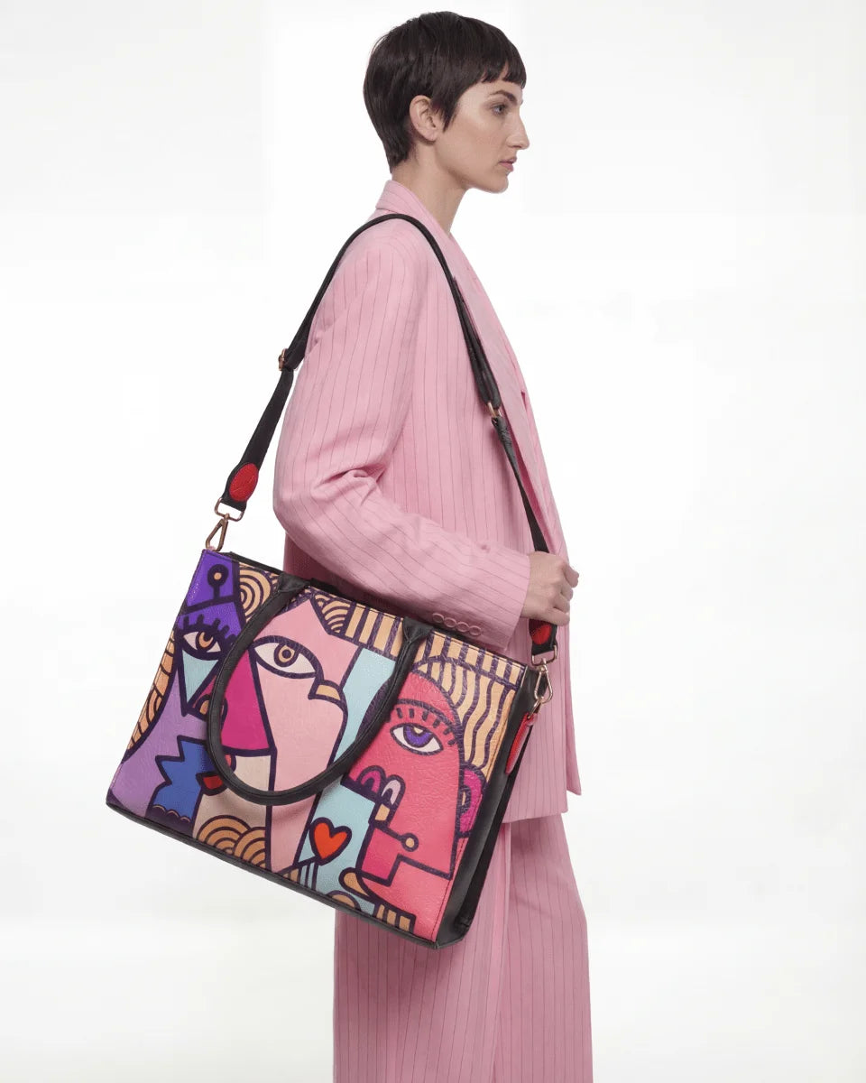Woman holding a colorful handbag with abstract face design on a white background