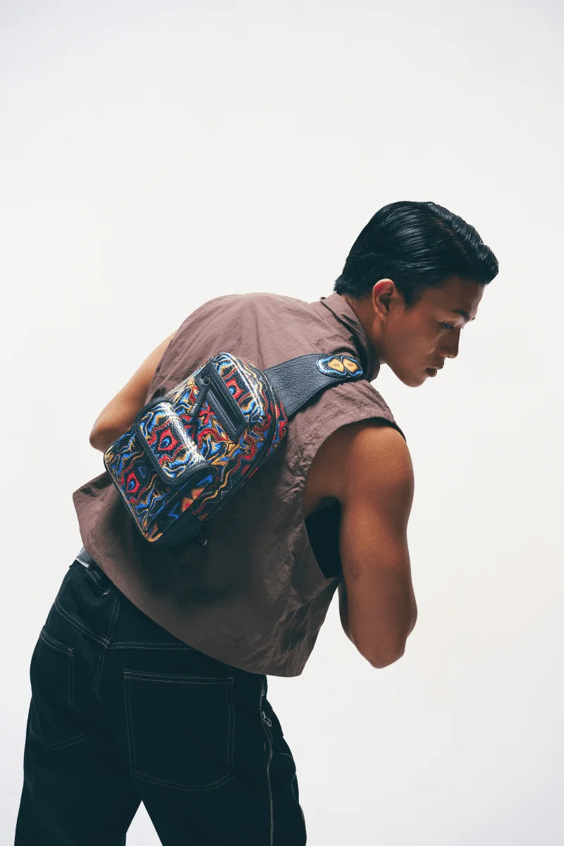 Back view of a Person wearing a black crossbody sling bag with a plain background