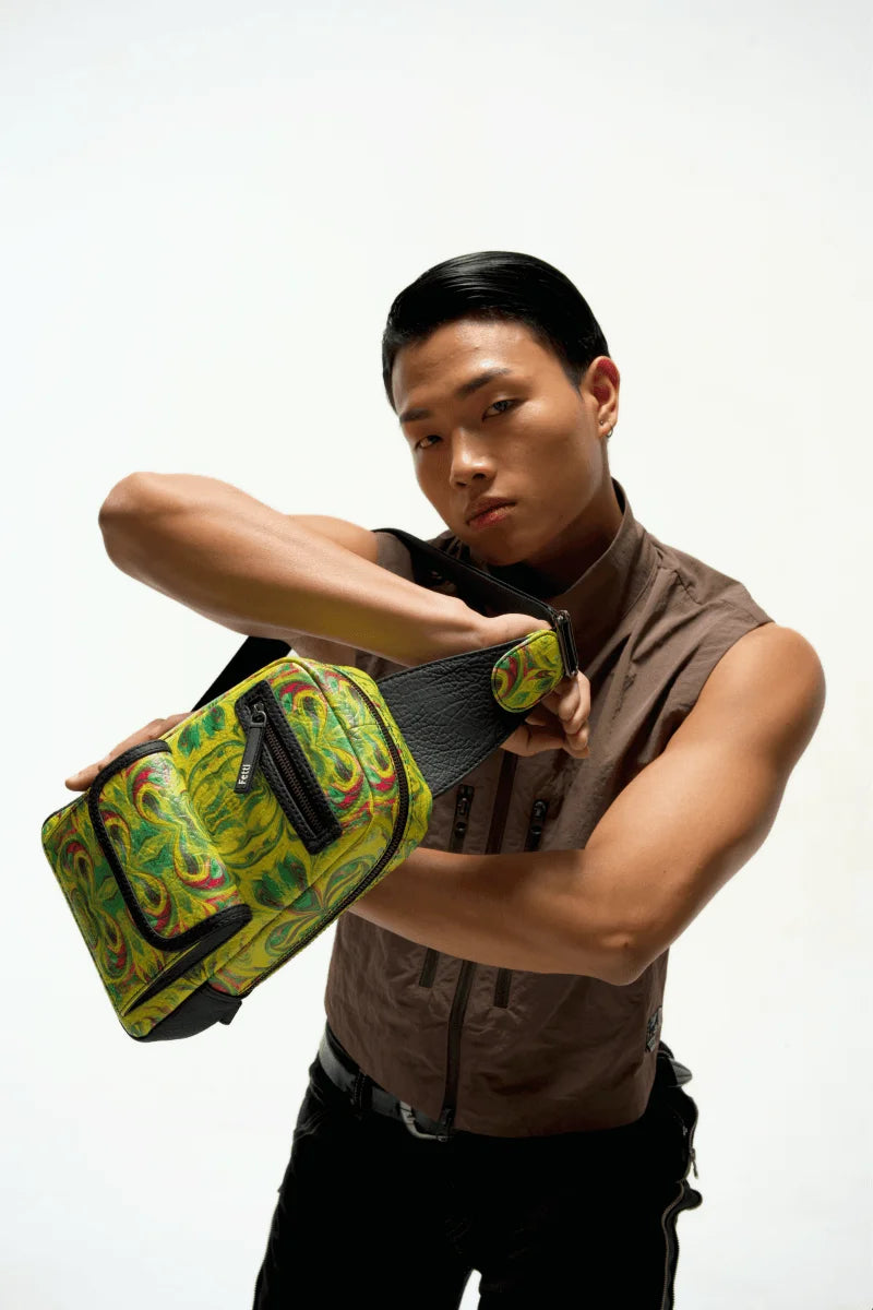 Man holding a Kosmic Immersion helios sling bag against a white background