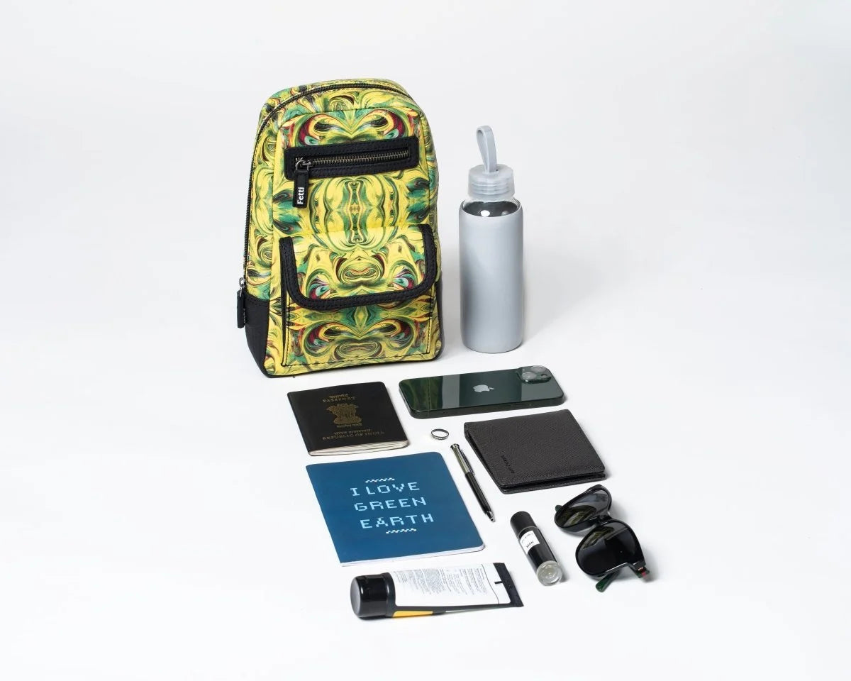 Compact travel sling bag carrying everyday essentials, including a water bottle, phone, and books, on a white background